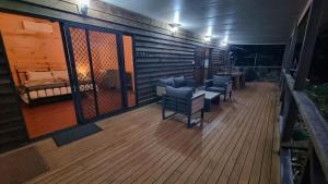 a wooden deck with chairs and a bed on it at Bellthorpe Retreat in Bellthorpe