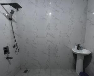a white tiled bathroom with a sink and a shower at Malindi Mambrui Villa in Malindi +8 photos