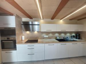 a kitchen with white cabinets and stainless steel appliances at La Fontchaude, gîte de charme au cœur de la nature à Cabrespine in Cabrespine
