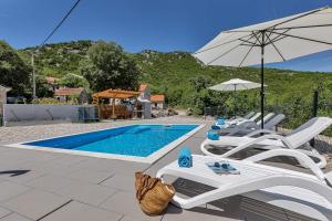 a pool with chairs and an umbrella and a swimming pool at Villa Magdalena in Zavojane