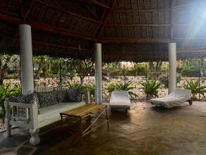 a porch with a couch and a table and chairs at Malindi Mambrui Villa in Malindi