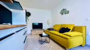 a yellow couch in a living room with a tv at Apartment Bellaria in Jadranovo