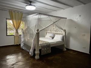 a bedroom with a white bed with a canopy at Malindi Mambrui Villa in Malindi