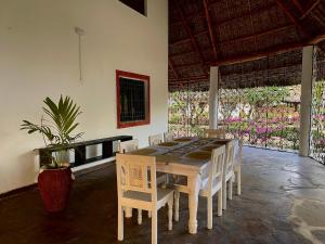 a dining room with a table and chairs and flowers at Malindi Mambrui Villa in Malindi