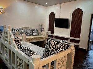 a room with two beds with zebra pillows and a tv at Malindi Mambrui Villa in Malindi