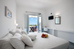 a white bedroom with a white bed and a balcony at Flora & Agelos Studios - Paros in Chrissi Akti