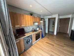 a kitchen with wooden cabinets and a washer and dryer at Odyssée Atlantique Blue beach - Sidi Rahal - famille seulement in Sidi Rahal