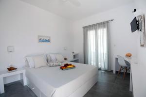 a white bedroom with a bed with a tray of fruit on it at Flora & Agelos Studios - Paros in Chrissi Akti +50 photos