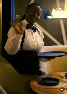 a man in a suit and bow tie holding a plate at Kim Royal Hotel and Suites in Festac Town