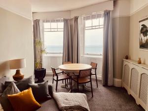 a living room with a table and chairs and the ocean at Stunning seafront apartment in Brighton & Hove