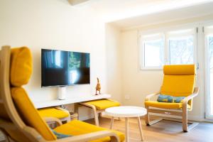 a living room with yellow chairs and a tv at Relais Lungolago Gavirate in Gavirate