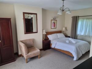 a bedroom with a bed and a chair and a mirror at Maryland Cottage Nr Gatwick in Godstone