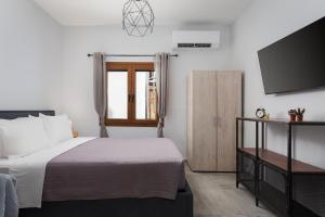 a bedroom with a bed and a flat screen tv at Utopia Suites in Egina