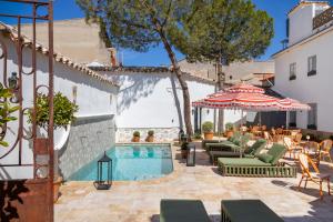 a pool with chairs and an umbrella next to a building at Hotel Boutique Casa Treviño in Campo de Criptana