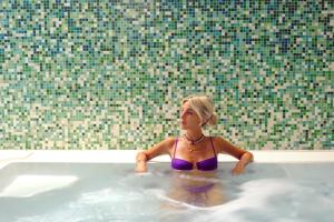a girl in a purple bikini sitting in a bathtub at MySEELE Garda Active Hotel in Nago-Torbole