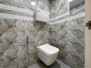 a bathroom with a toilet and a stone wall at Hotel Platinum in Mumbai