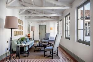 a living room with a couch and chairs and windows at Hotel Boutique Casa Treviño in Campo de Criptana
