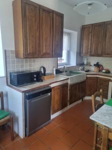 a kitchen with wooden cabinets and a black dishwasher at Wildflowers House - JApartments in Genoa
