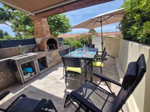 a patio with a table and chairs and an umbrella at Nouveau ! Maison Dora 4-6 pers à St Pierre La Mer proche de la plage et de toutes commodités à pied in Saint Pierre La Mer