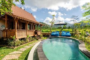 a resort pool with blue chairs and an umbrella at Green Labak 1 in Silebeng