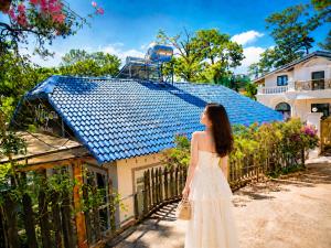 a woman in a white dress standing in front of a house at May Garden Home in Da Lat