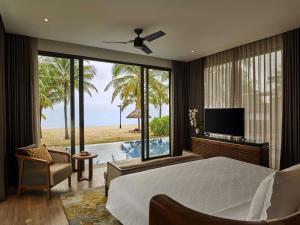 a bedroom with a bed and a view of the beach at Mövenpick Villas & Residences Phu Quoc in Phú Quốc
