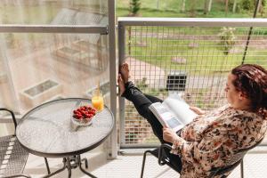 a woman sitting at a table reading a book and looking out a window at Sume by Larsen in Tallinn +55 photos