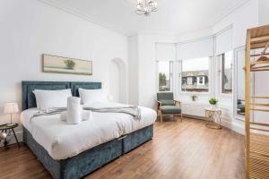 a white bedroom with a large bed and a chair at Scott Suite - Donnini Apartments in Kilmarnock