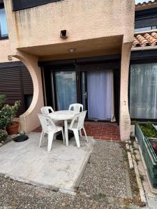 a white table and chairs on a patio at 423 Résidence Aphrodite naturiste in Leucate-Plage +3 photos