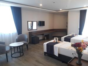 ein Hotelzimmer mit zwei Betten, einem Tisch und Stühlen in der Unterkunft Evdirhan Otel in Dosemealti