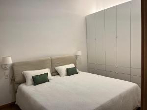 a bedroom with a white bed with two green pillows at Central Bilbao, 3min walk to Guggenheim with AC in Bilbao