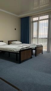 a room with two beds and a large window at Ак-Кеме отель in Bosteri