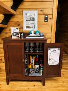 a small wooden cabinet with drinks in it at Alpina Village, Jacuzzi Climatizado, Montaña, Fogata, Jarabacoa in Jarabacoa