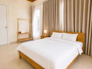 a bedroom with a large white bed and a window at May Garden Home in Da Lat +1 photo