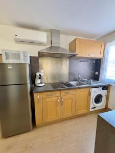 a kitchen with a stainless steel refrigerator and a dishwasher at Studio avec Wi-Fi, à 5mn de la Centrale du Bugey in Loyettes