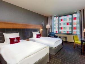 a hotel room with two beds and a desk at MÖVENPICK Hotel Stuttgart Airport in Leinfelden-Echterdingen +164 photos