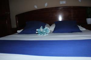 a bed with blue pillows and a blue flower on it at Residencial Beleza in Mindelo