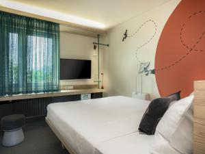 a bedroom with a bed and a flat screen tv at ibis Styles Darmstadt in Darmstadt +94 photos