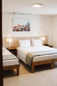 a bedroom with two beds and a painting on the wall at Hotel Triveneto Gramado in Gramado