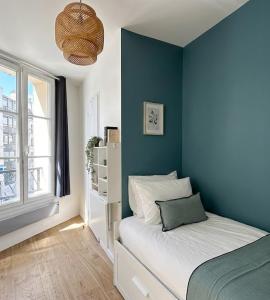 a bedroom with a blue wall with a bed and a window at Hôtel My Suite Paris in Paris
