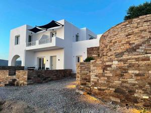 a large white house with a stone wall at IosAgnanti in Ios Chora