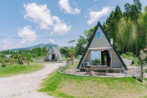 a small house with a gambrel roof on a dirt road at 自然満喫 野上平ロッジ in Kirishima