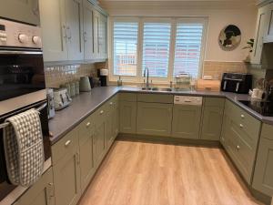 a kitchen with green cabinets and a wooden floor at Ivy House in Stockbridge +5 photos