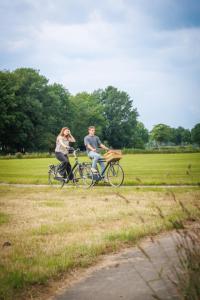 a man and woman riding bikes in a field at Buiteninn in Rijssen