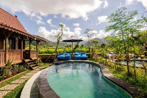 a pool at a resort with blue chairs and an umbrella at Green labak 2 in Silebeng