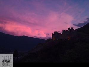 a castle sitting on top of a hill at sunset at Alla Rupe 8 - bilocale con vista sulle Alpi in Grosotto