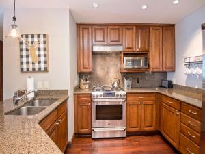 a kitchen with wooden cabinets and a stainless steel stove at Ascent Condo 111 in Avon