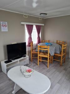 a living room with a table and a dining room at Mobilhome empl 28 in Saint-Martin-aux-Buneaux