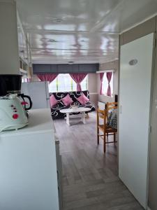 a kitchen and living room with pink curtains at Mobilhome empl 28 in Saint-Martin-aux-Buneaux