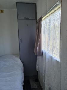 a bedroom with a window with a curtain and a bed at Mobilhome empl 28 in Saint-Martin-aux-Buneaux